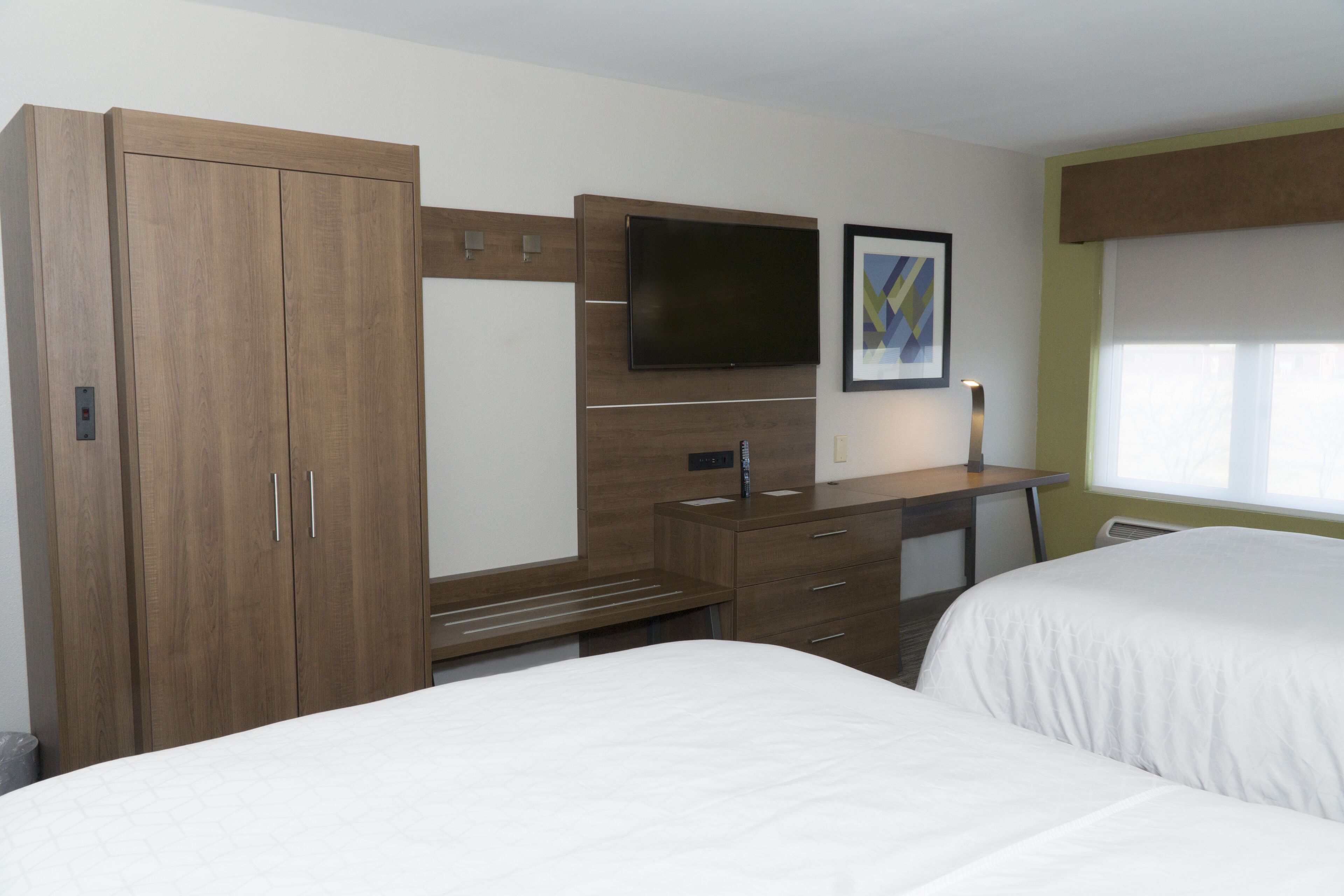 Una habitación de hotel con cama, escritorio, televisión y armario.