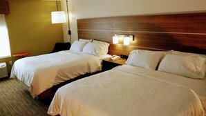 A hotel room with two beds, a nightstand with a lamp, and a window with blinds. - Holiday Inn Express Hotel & Suites Madison by IHG (Madison)