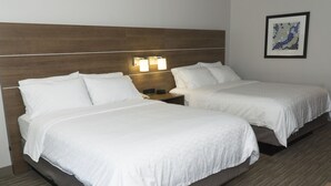 A hotel room with two beds, a wooden headboard, bedside lamps, and a framed artwork on the wall. - Holiday Inn Express Hotel & Suites Madison by IHG (Madison)