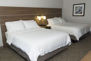 Habitación de hotel con dos camas, cabecero de madera, lámparas de noche y una obra de arte enmarcada en la pared.