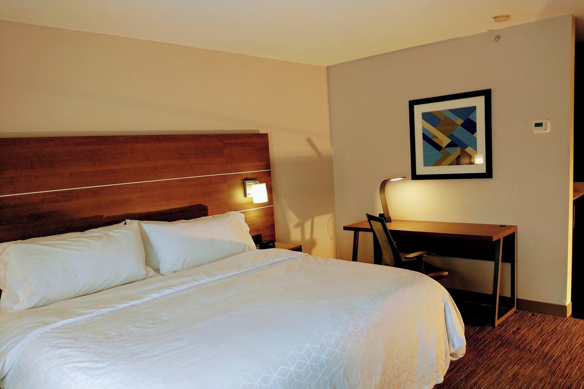 Una habitación de hotel con una cama grande, un escritorio y una silla.