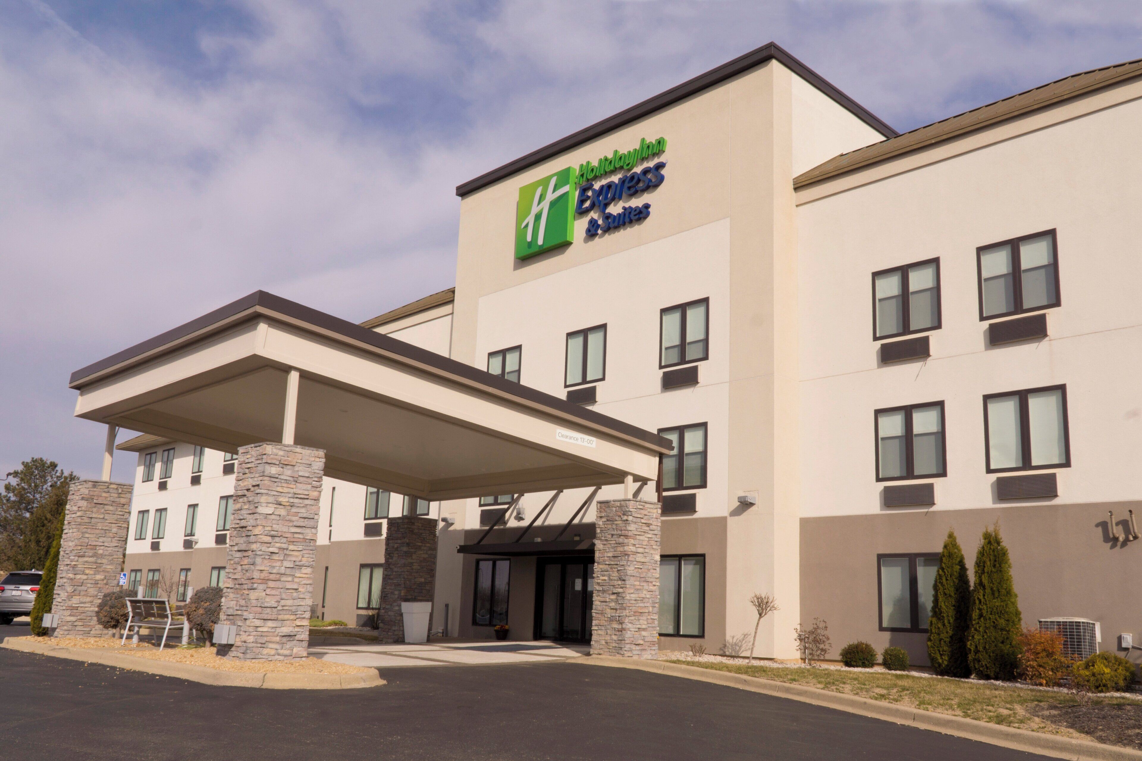 A Holiday Inn Express hotel with a covered entrance, stone pillars, and a clear sky.