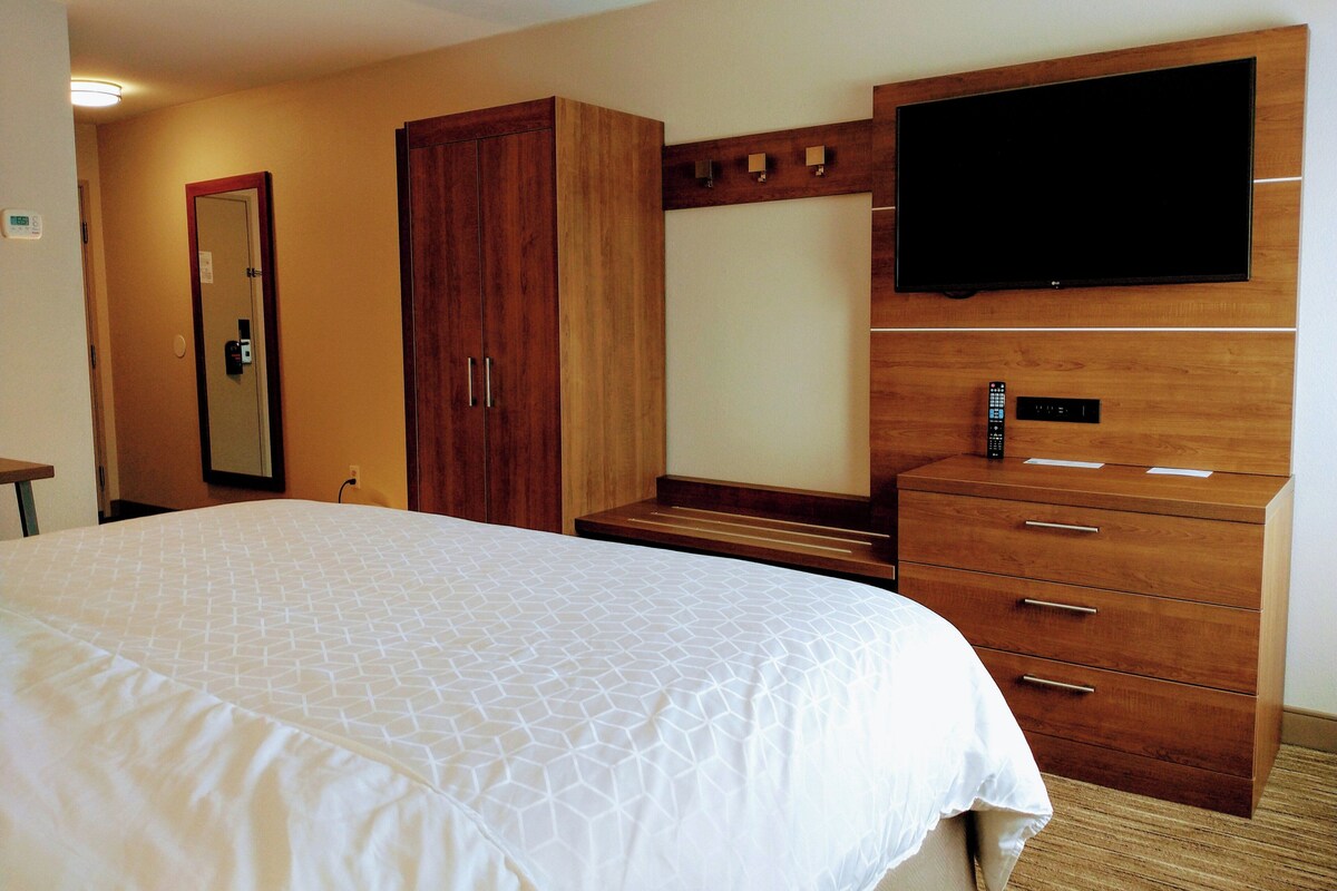 Una habitación de hotel con una cama grande, un armario, un televisor y un escritorio.