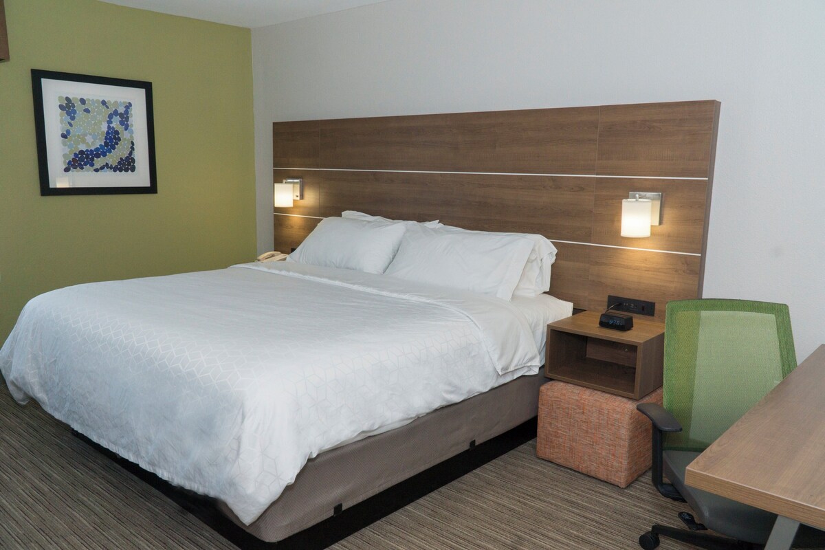 Una habitación de hotel con una cama grande, un escritorio, una silla y dos lámparas de noche.