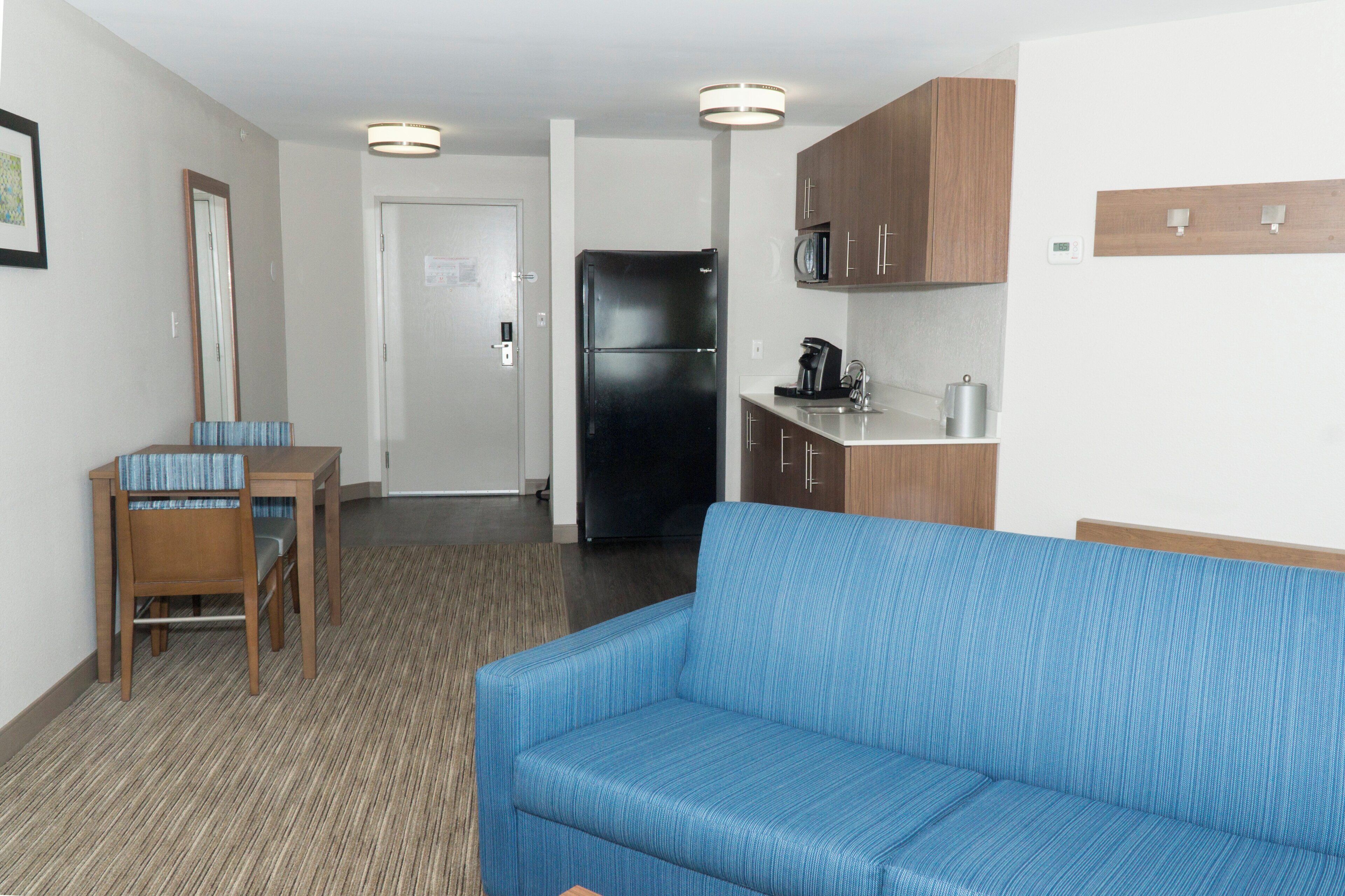 Ein kleines Hotelzimmer mit Küchenzeile, einem Essbereich mit Tisch und Stühlen sowie einer Couch.