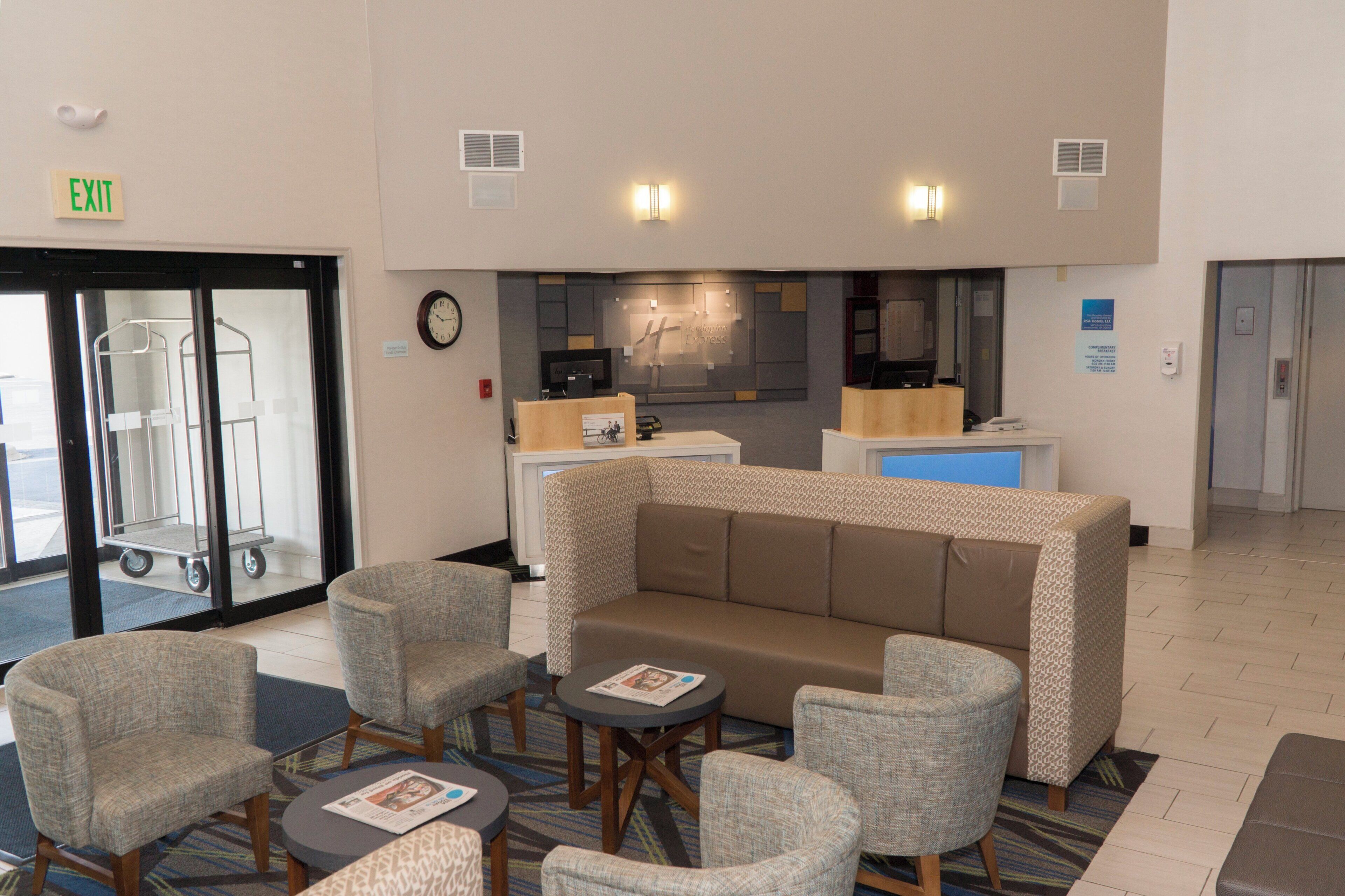 A hotel lobby with a reception desk, seating area, and an exit sign.