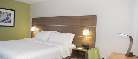 Habitación de hotel con una cama grande, dos mesitas de noche con lámparas, una pequeña mesita auxiliar de madera, una silla verde y un escritorio con lámpara.