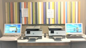 A desk with two HP printers, a keyboard, and a mouse. There are two monitors displaying desktop backgrounds. - Holiday Inn Express Hotel & Suites Madison by IHG (Madison)