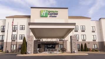 Un hotel Holiday Inn Express & Suites con fachada moderna, pilares de piedra y cielo despejado.