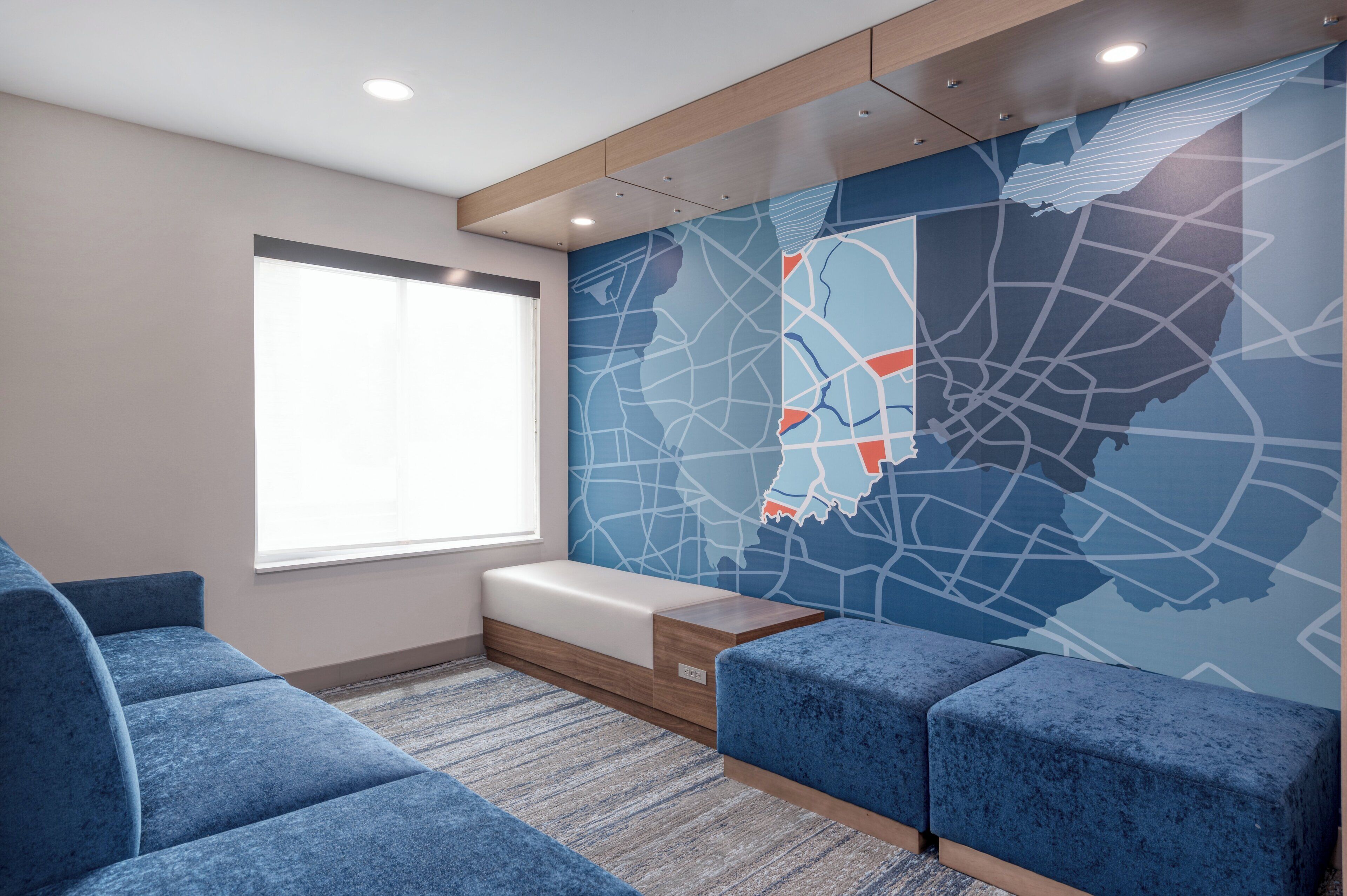Un espace d’attente moderne avec un canapé bleu, un banc et un mur décoré d’une carte de la ville.