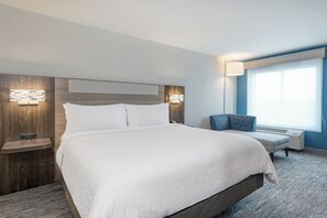 Habitación de hotel con una cama grande, una silla, un escritorio y una ventana.