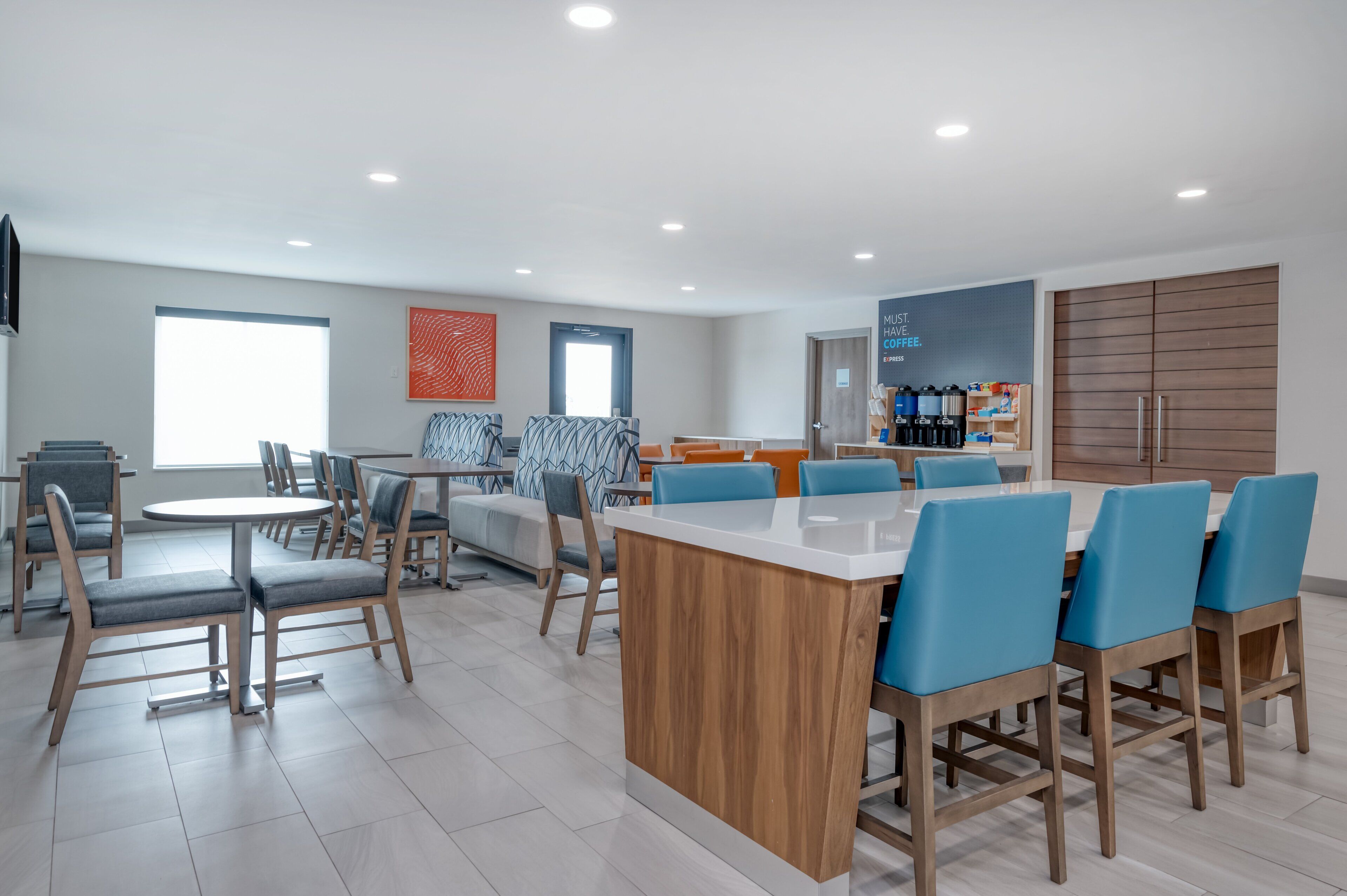 A modern kitchen area with a central island, bar seating, and a coffee station.