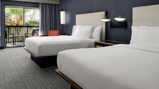 A hotel room with two beds, a balcony with a view, and a desk with a lamp. - Courtyard by Marriott Stockton (Stockton)
