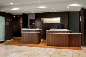 A reception desk with a wooden finish, a digital screen, and a sign indicating the F.A.C.P. area. - Courtyard by Marriott Stockton (Stockton)