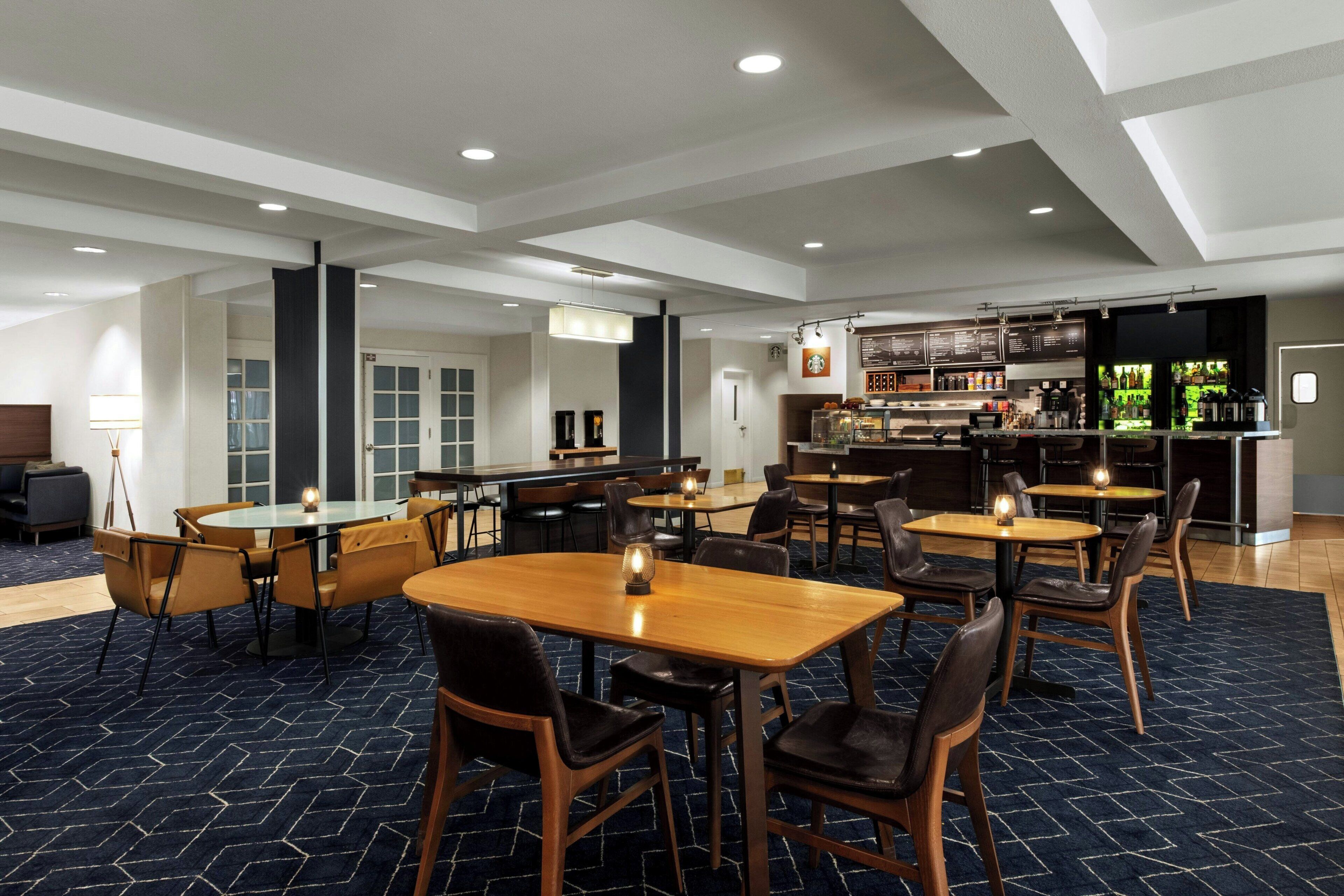 Um saguão de hotel com diversas áreas de estar, um bar e uma escadaria.
