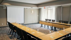 A conference room with a long table, chairs, a projector screen, and a large window with curtains. - Courtyard by Marriott Stockton (Stockton)
