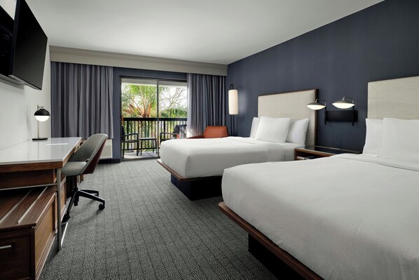 A hotel room with two beds, a desk, a chair, a TV, and a balcony with curtains. - Courtyard by Marriott Stockton (Stockton)