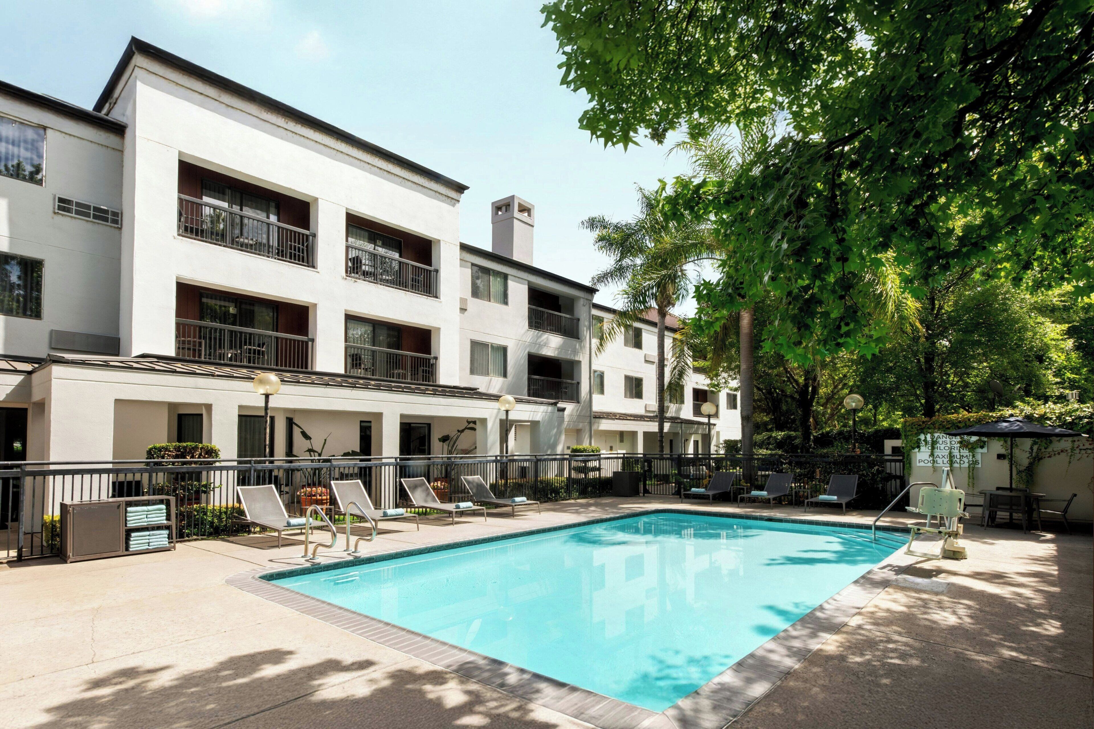 A swimming pool with lounge chairs and a building with balconies.