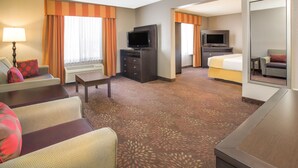 Une chambre d’hôtel équipée d’un canapé, d’une télévision, d’un lit, d’un bureau et d’un miroir.