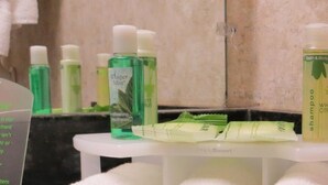 Des articles de toilette sont posés sur une étagère blanche dans une salle de bain.