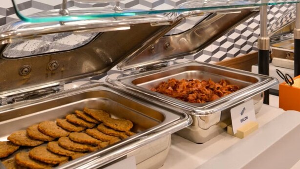 Un buffet avec des plateaux de saucisses de dinde, de bacon et de biscuits, chacun étant clairement étiqueté.