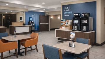 A modern coffee shop with tables and chairs, a refrigerator, and a coffee machine.