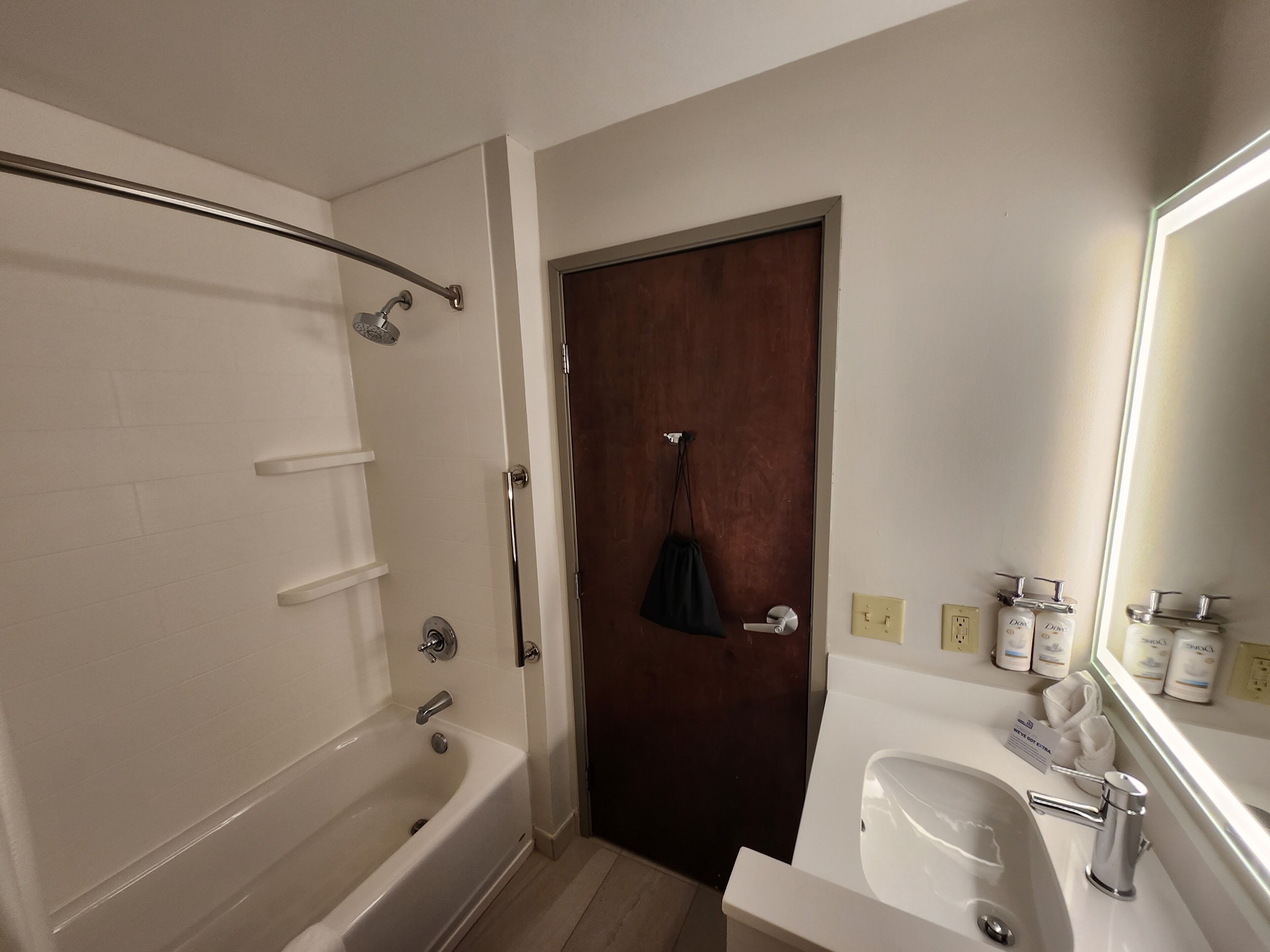 A bathroom with a bathtub, a sink, and toiletries on the counter.