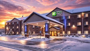 Ein Holiday Inn Express Gebäude mit Backsteinfassade, überdachter Eingangsparte und einem Parkplatz mit Schneebedeckung.