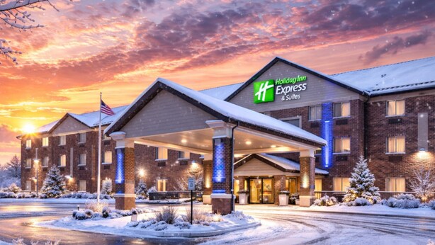 Ein Holiday Inn Express & Suites Gebäude mit überdachter Einfahrt, Backsteinfassade und verschneiter Umgebung.