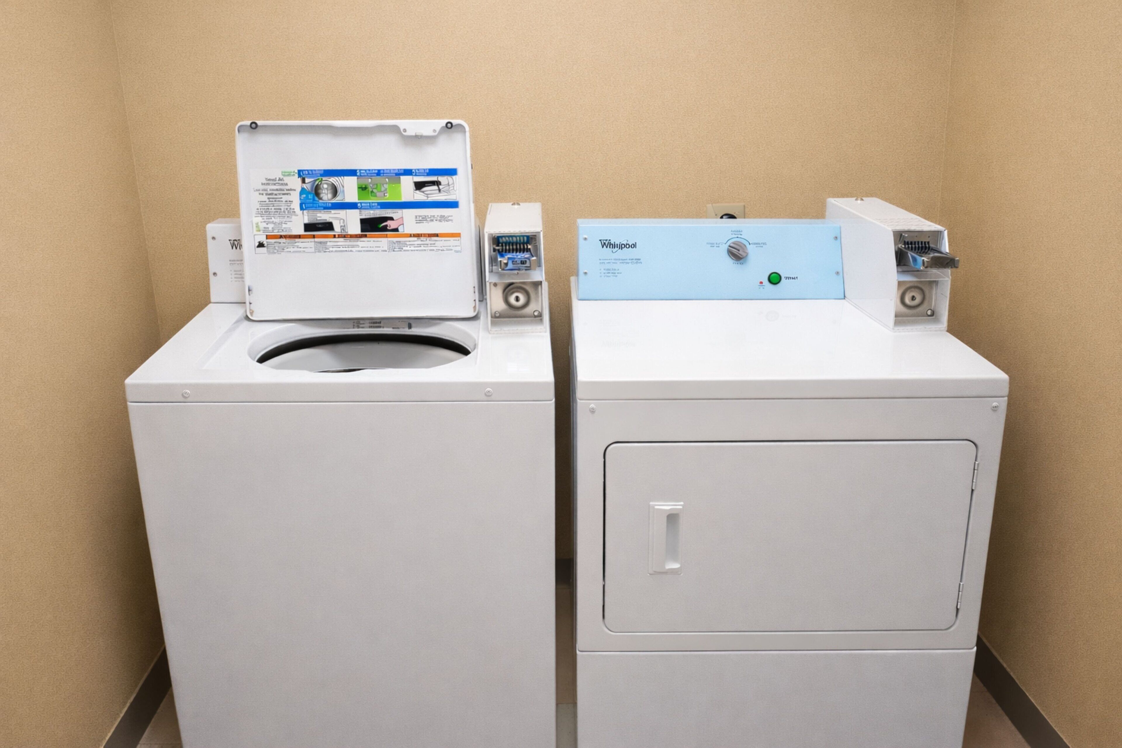 Two front-loading washing machines in a corner with beige walls.