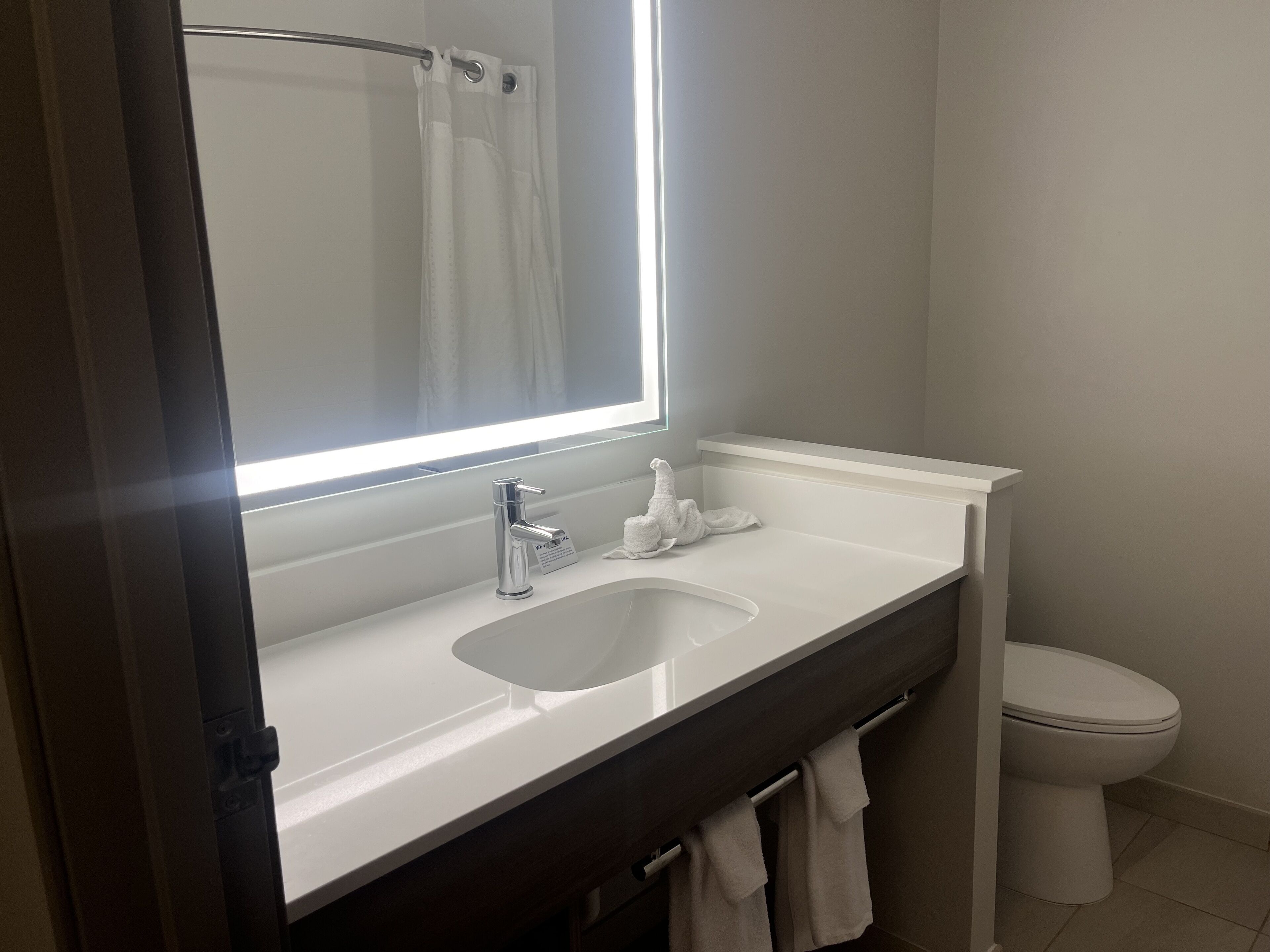 Une salle de bain avec un lavabo blanc, un miroir, des toilettes et un porte-serviettes.