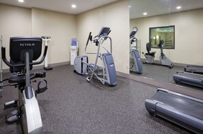 Ein Fitnessstudio mit verschiedenen Trainingsgeräten, darunter Laufband, Crosstrainer und Ergometer.