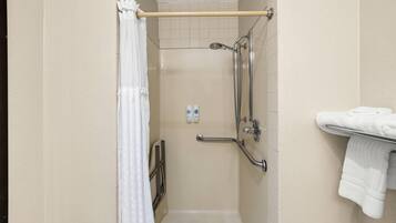 Un espacio con ducha, barra de apoyo, toallero y cabezal de ducha.