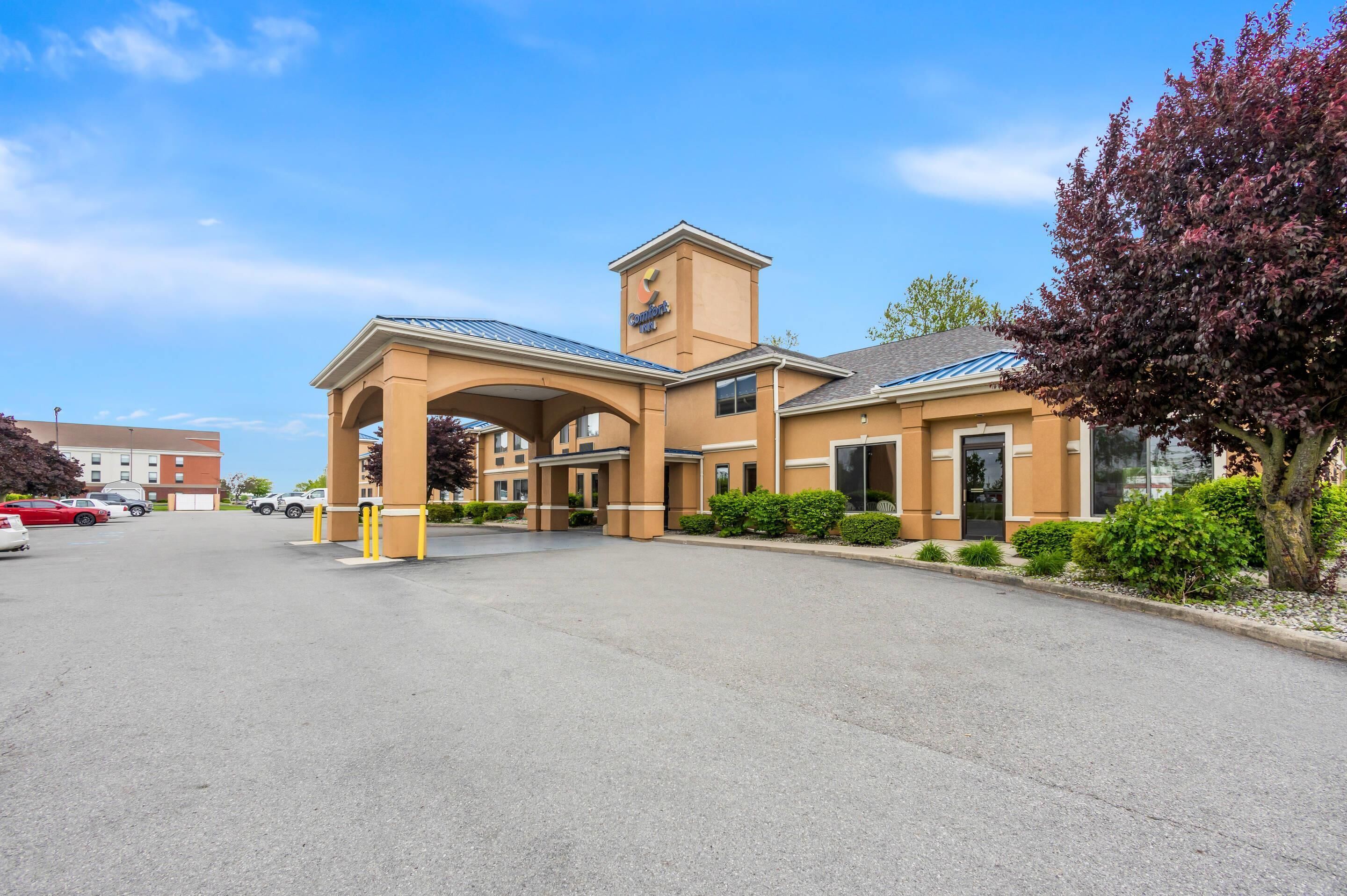 A hotel entrance with a covered driveway and a prominent sign.