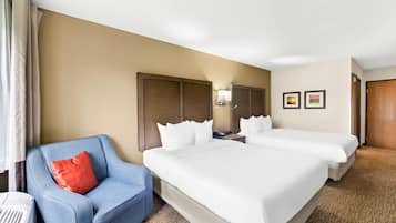 Habitación de hotel con dos camas, un sillón azul, un calentador y una lámpara fijada a la pared.