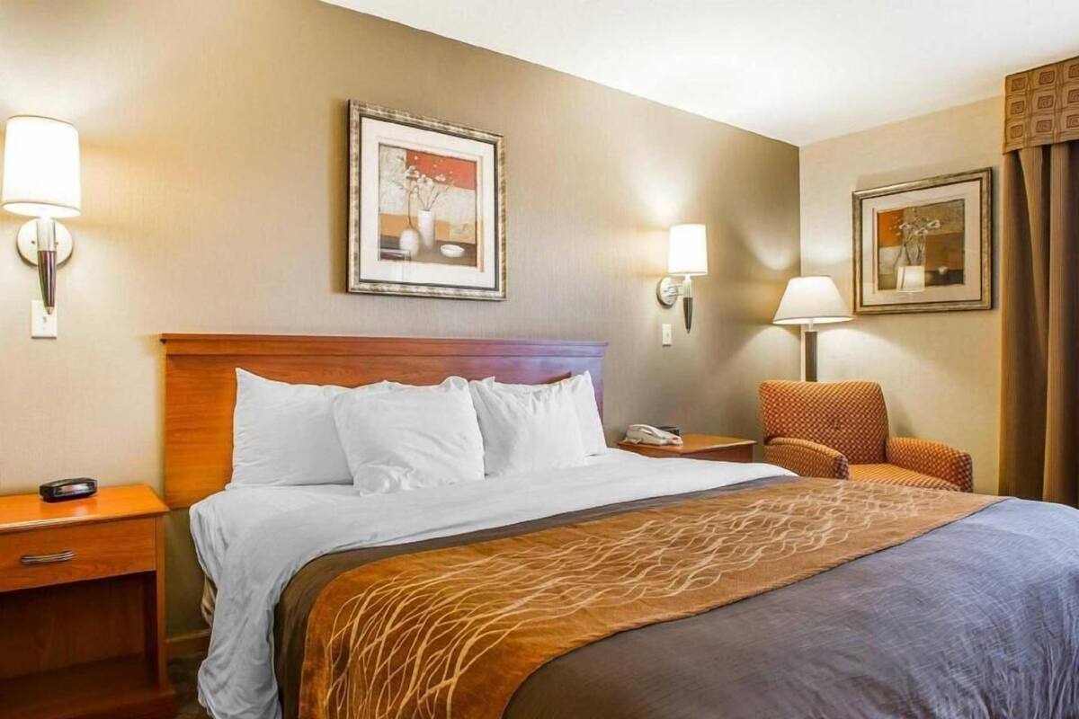 A hotel room with a bed, bedside tables, a chair, and two wall-mounted lamps.