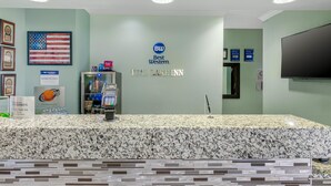 A reception area with a marble counter, an American flag, and a Best Western sign. - Best Western Teal Lake Inn (Mexico)