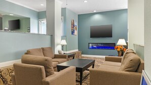 A living room with beige sofas, a coffee table, and a flat-screen TV mounted on the wall. - Best Western Teal Lake Inn (Mexico)