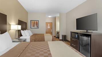 Habitación de hotel con cama, escritorio con lámpara, televisión, refrigerador y microondas.