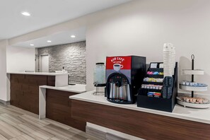 Reception area with a reception desk, coffee machine, and pastry stand.