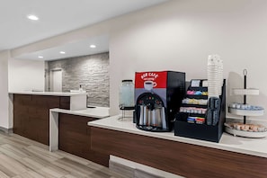 Reception area with a reception desk, coffee machine, and pastry stand.