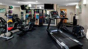 Un gimnasio con cintas de correr, bicicletas estáticas y diversos equipos de ejercicio.