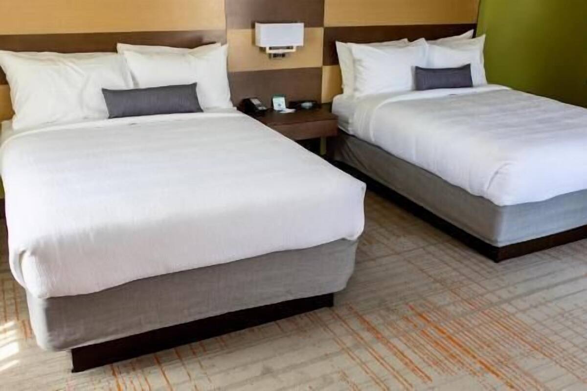 Ein Hotelzimmer mit zwei Betten, einem Nachttisch und einer Wandlampe.