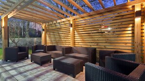 Un patio al aire libre con muebles de mimbre bajo una pérgola de madera.