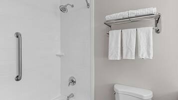 Un bagno con doccia, WC e porta asciugamani con asciugamani.