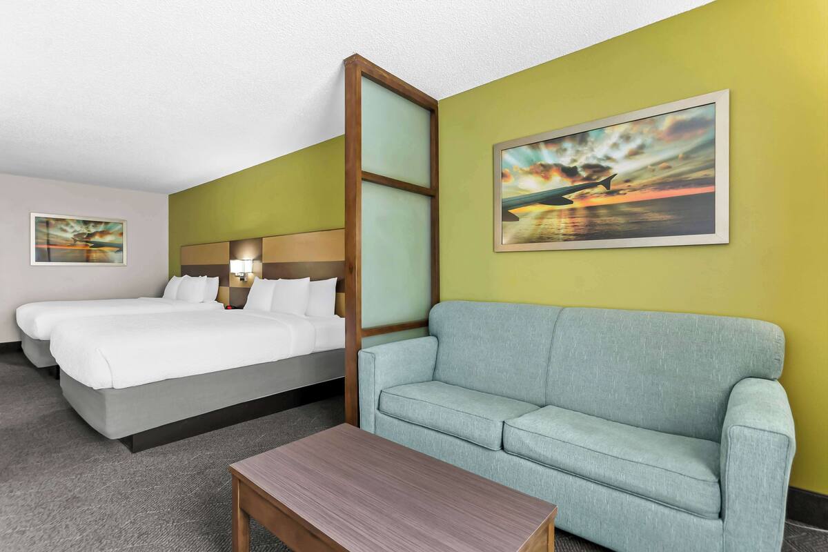 Ein Hotelzimmer mit Bett, Sofa und einem Gemälde eines Flugzeugs.