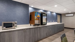 A modern kitchen with a microwave, refrigerator, and juice dispenser.