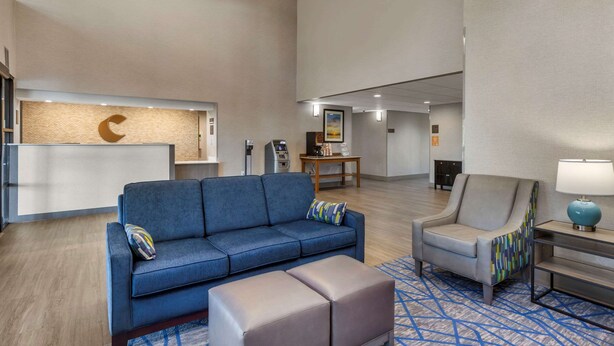A spacious lobby with a blue sofa, a grey armchair, and a patterned rug.