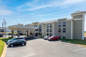 A hotel with a parking lot, multiple entry points, and a clear sky.