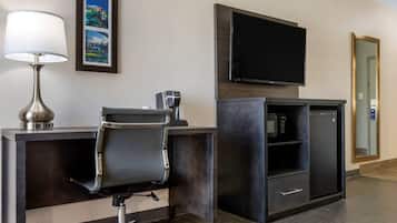 Habitación de hotel con escritorio, silla, cafetera, televisor, microondas y espejo.
